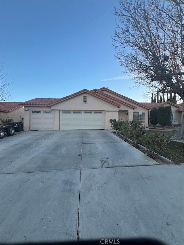 view of front of home with an attached garage, concrete driveway, and stucco siding