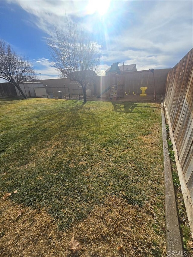 view of yard featuring a fenced backyard and a playground