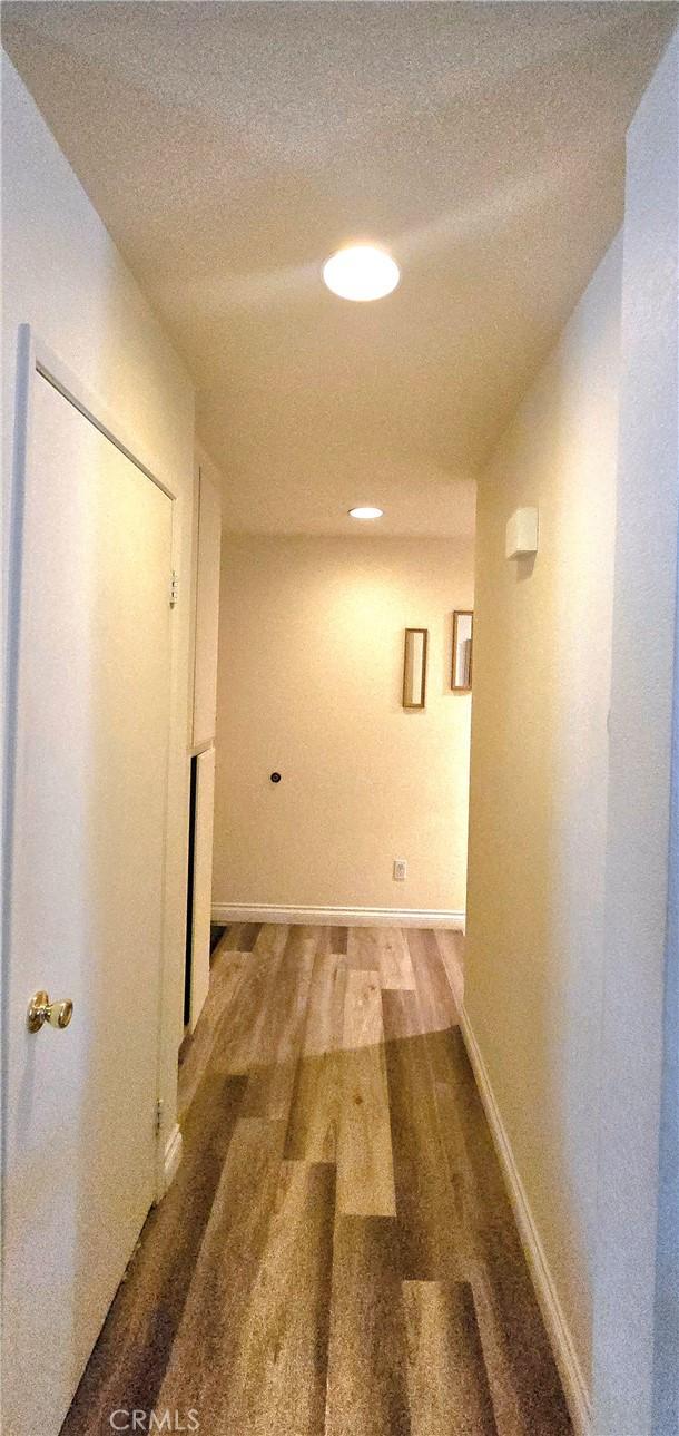 corridor with a textured ceiling and hardwood / wood-style flooring