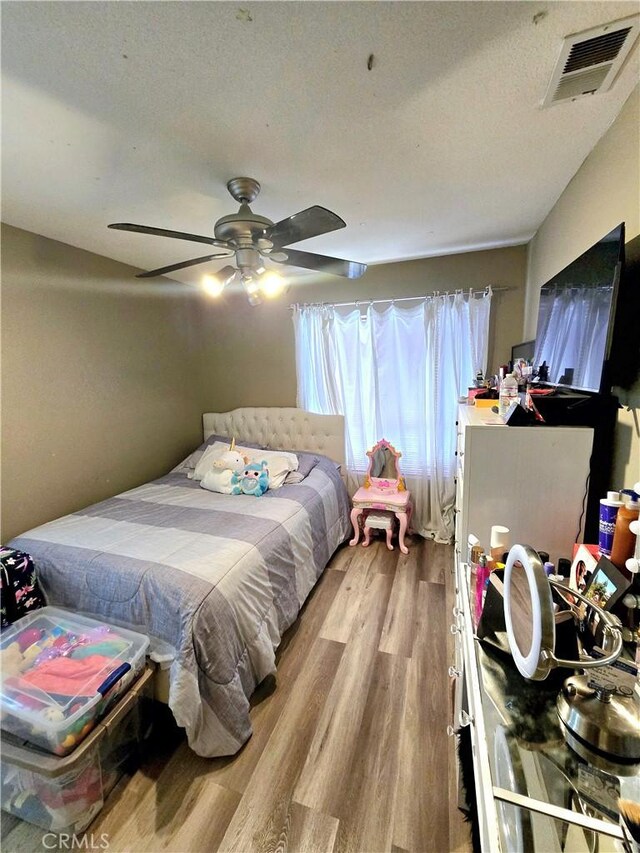 bedroom featuring ceiling fan, light wood-type flooring, and a textured ceiling