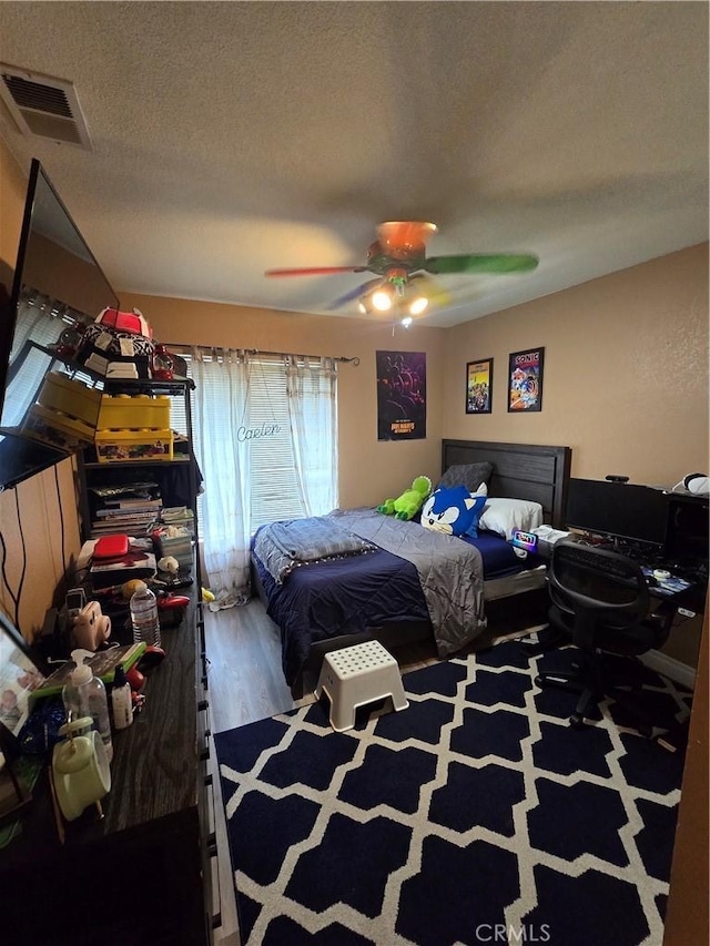 bedroom with ceiling fan, a textured ceiling, and wood-type flooring