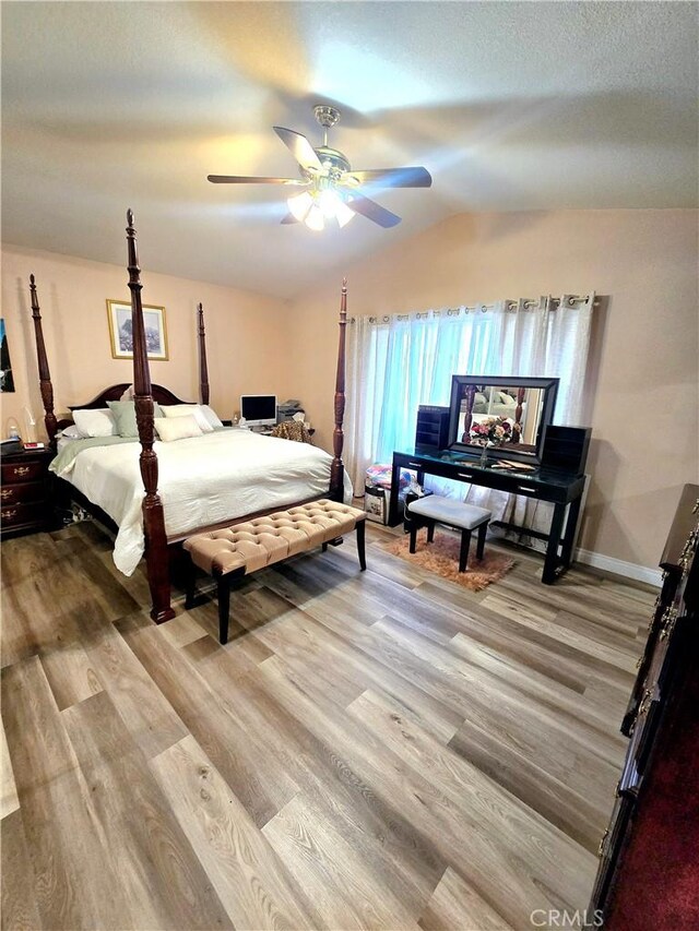 bedroom featuring ceiling fan, light hardwood / wood-style floors, and vaulted ceiling