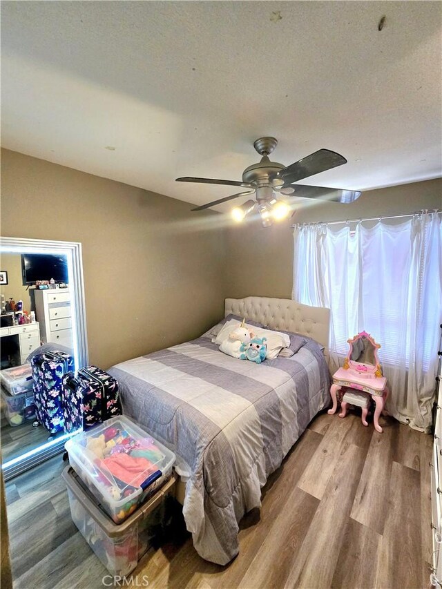 bedroom with ceiling fan, wood-type flooring, and a textured ceiling