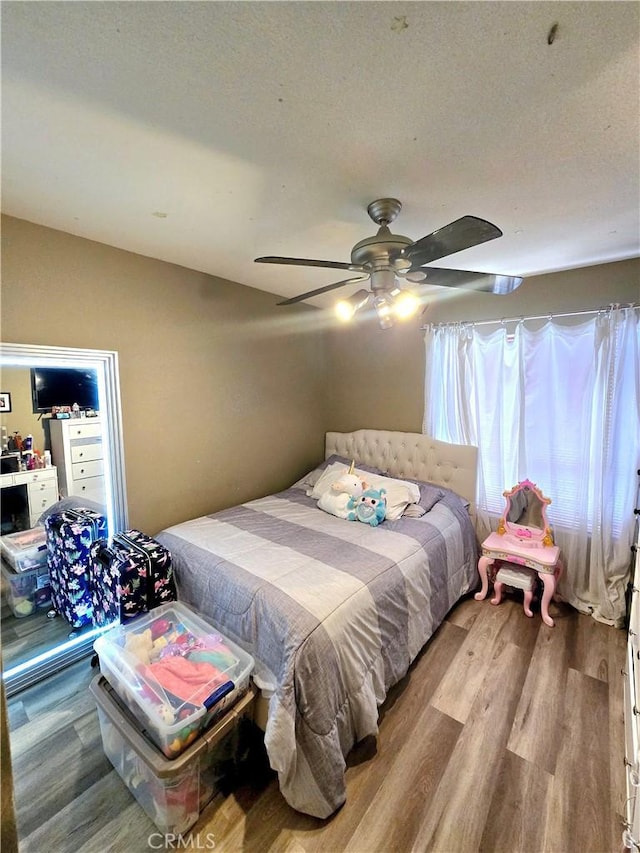 bedroom featuring ceiling fan, a textured ceiling, and wood finished floors