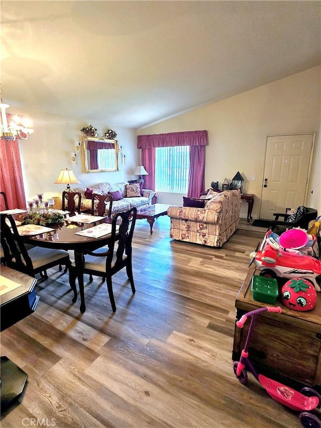 dining area featuring lofted ceiling, hardwood / wood-style floors, and a notable chandelier