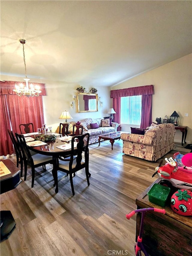 dining area featuring hardwood / wood-style flooring, lofted ceiling, and an inviting chandelier