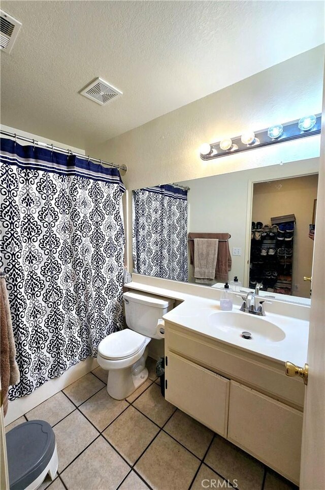 bathroom with toilet, vanity, tile patterned flooring, and a textured ceiling