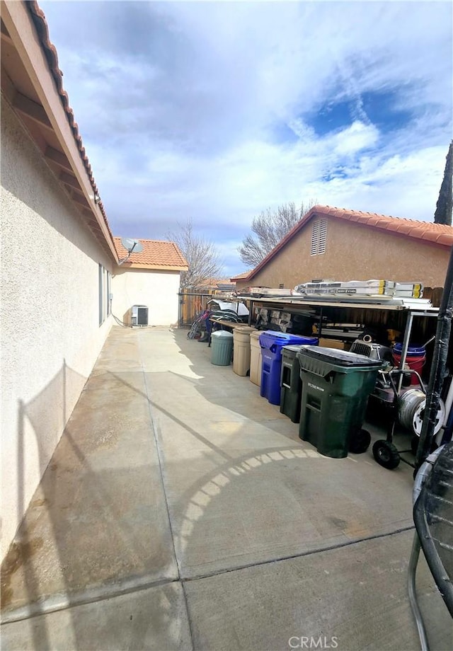 view of home's exterior featuring a tiled roof, fence, central AC unit, and stucco siding