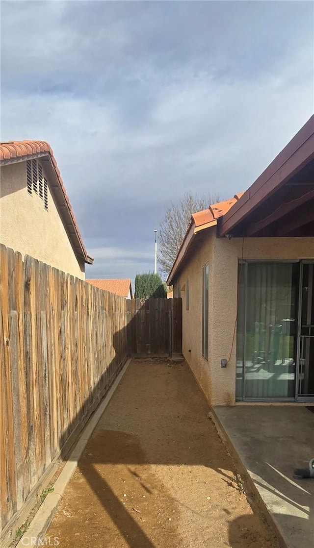 view of home's exterior with a tile roof, a patio area, fence, and stucco siding