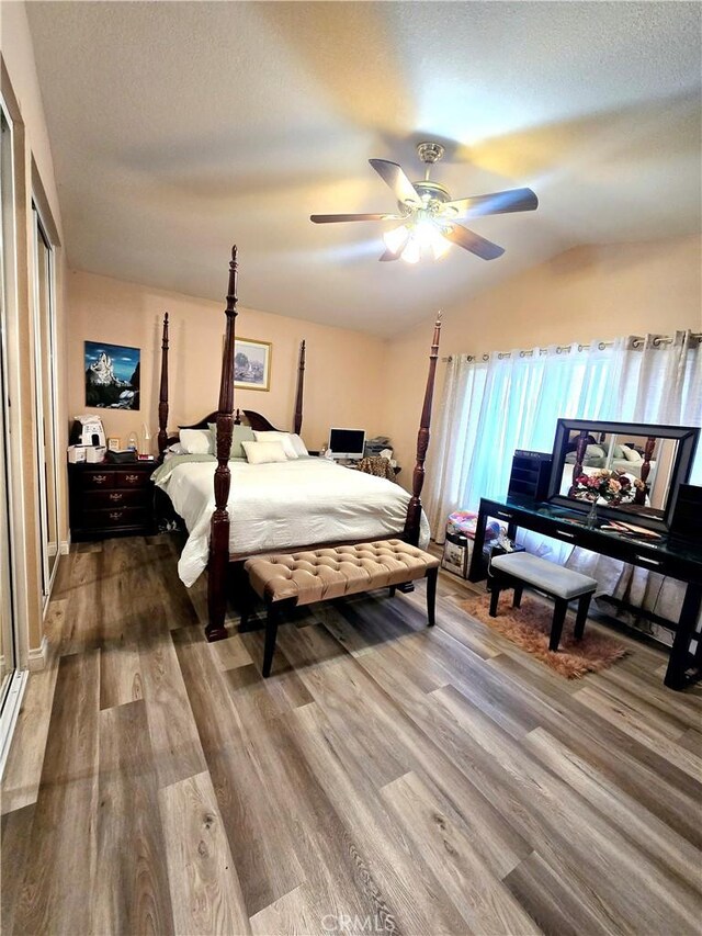 bedroom with ceiling fan, wood-type flooring, vaulted ceiling, and a textured ceiling