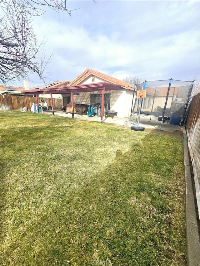 view of yard featuring a trampoline, a patio area, and a fenced backyard