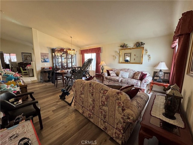 living area featuring lofted ceiling, wood finished floors, and a notable chandelier