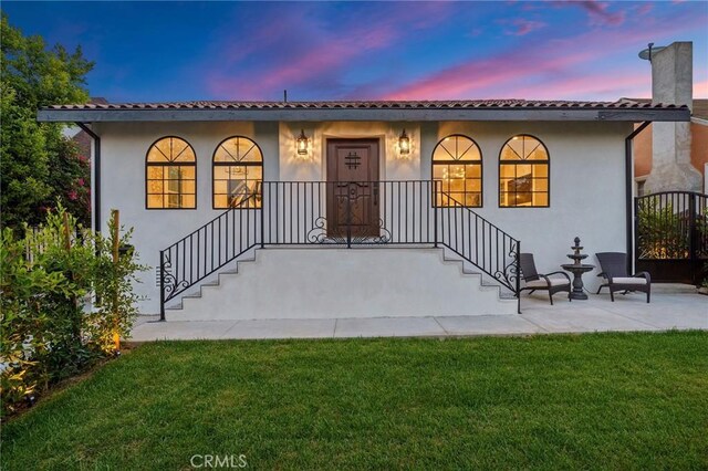 view of front of house with a yard and a patio