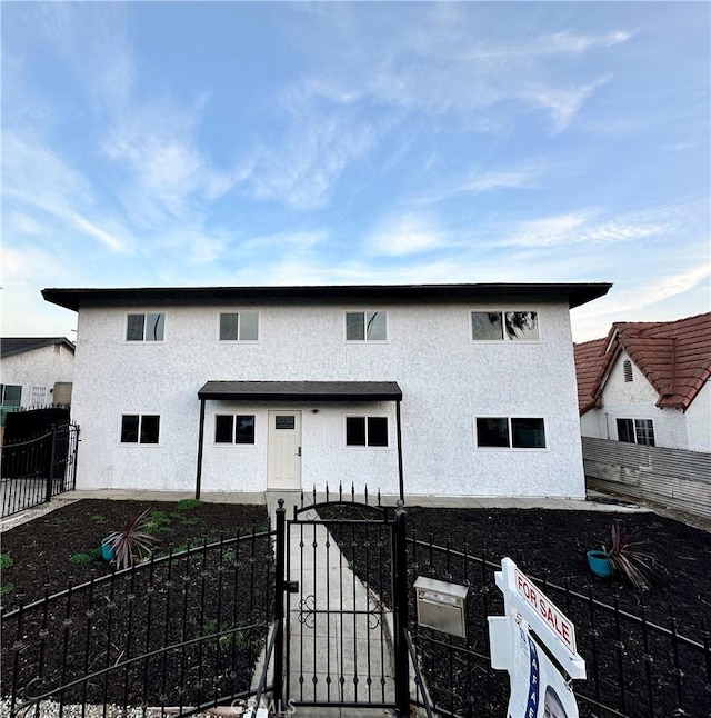 view of front of property with a fenced backyard, a gate, a patio, and stucco siding