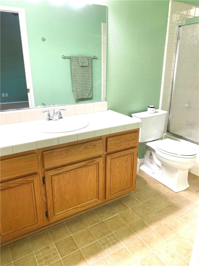 bathroom featuring a shower with shower door, toilet, and vanity