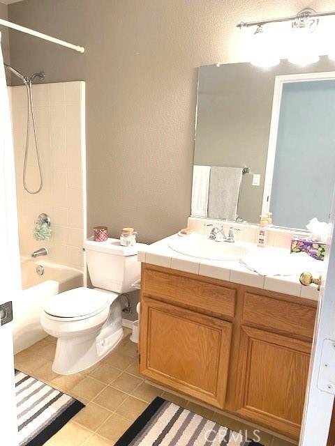 full bathroom featuring washtub / shower combination, toilet, tile patterned floors, and vanity