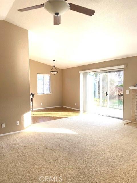 unfurnished living room featuring ceiling fan, light colored carpet, and vaulted ceiling