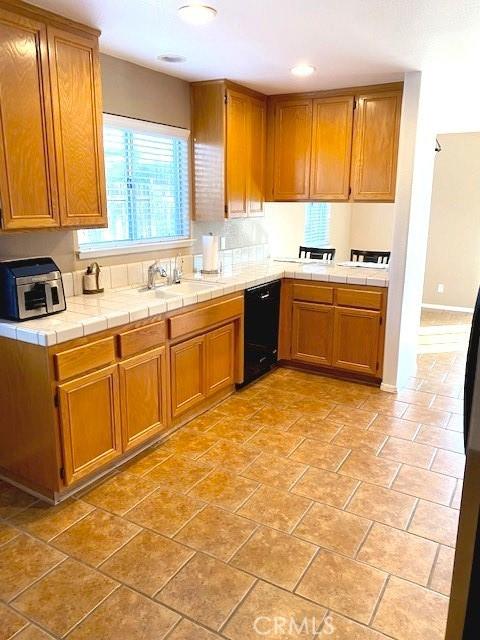 kitchen featuring sink, black dishwasher, and tile counters