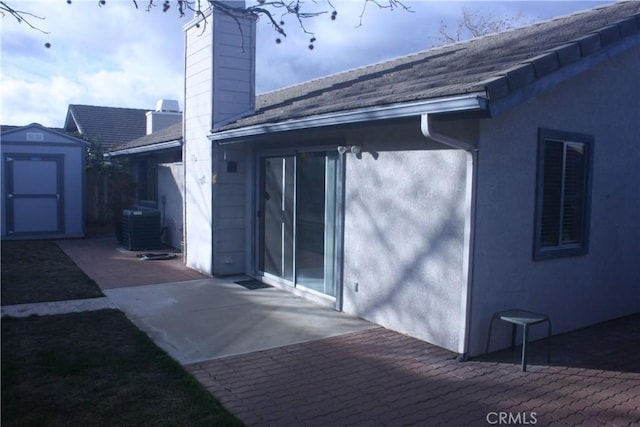 rear view of house featuring a patio area, central AC unit, and a shed