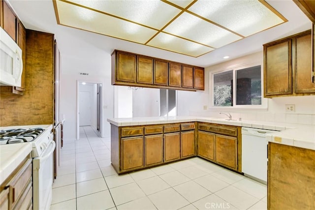 kitchen featuring sink, light tile patterned floors, tile countertops, and white appliances