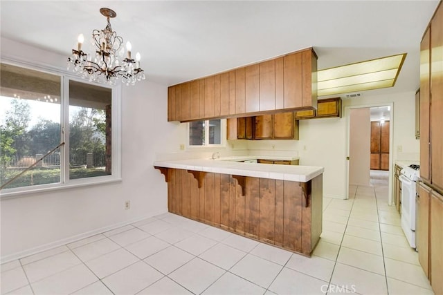 kitchen with decorative light fixtures, white range, kitchen peninsula, and a notable chandelier