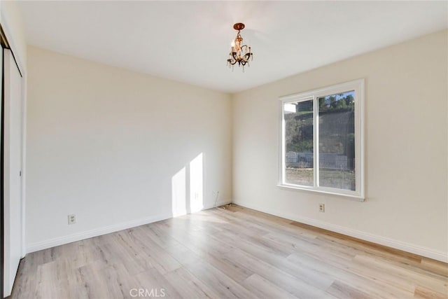 unfurnished room featuring a notable chandelier and light hardwood / wood-style floors