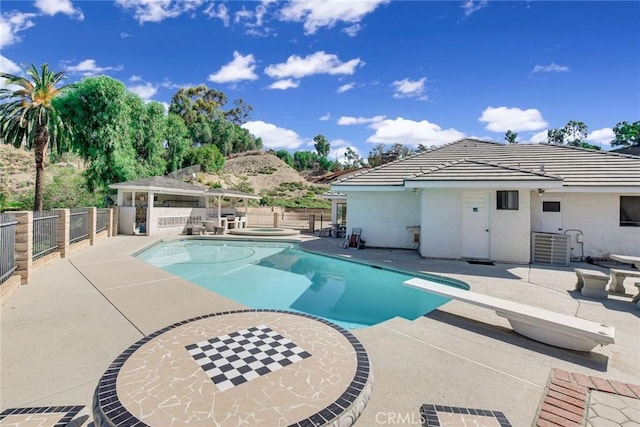 view of pool with a gazebo, a diving board, a patio, and an in ground hot tub