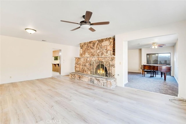 unfurnished living room featuring ceiling fan, a fireplace, and light hardwood / wood-style flooring