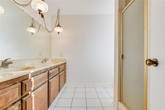 bathroom with a shower with shower door, vanity, and tile patterned flooring