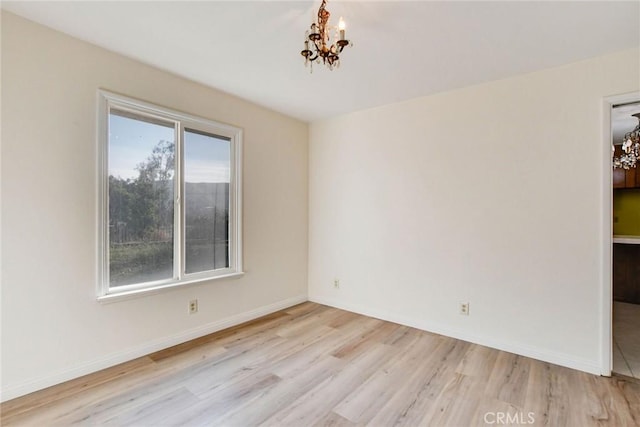 empty room with a chandelier and light hardwood / wood-style floors