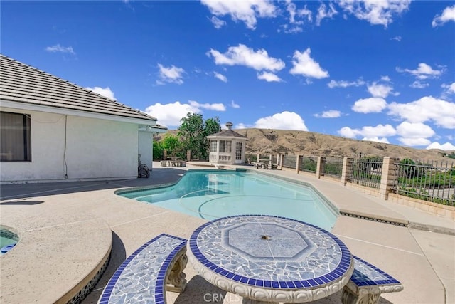 view of swimming pool with a patio area, a mountain view, and an outdoor structure