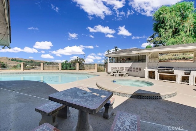 view of swimming pool with an in ground hot tub, a grill, exterior kitchen, and a patio