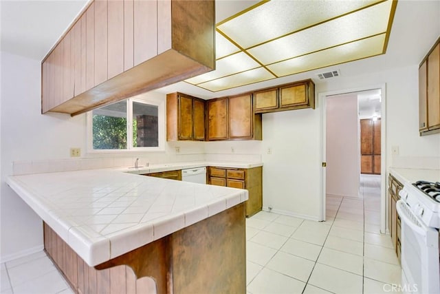 kitchen featuring light tile patterned flooring, tile countertops, kitchen peninsula, and white appliances