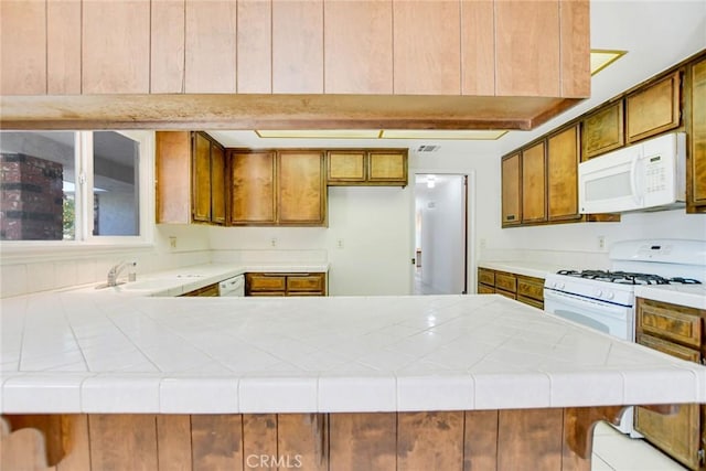 kitchen with tile counters, kitchen peninsula, and white appliances