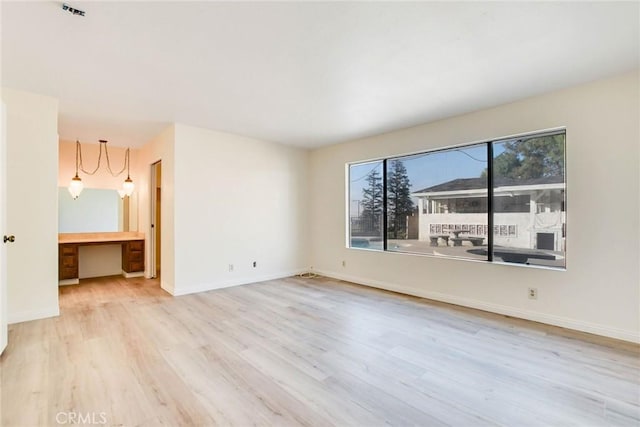 unfurnished room with light wood-type flooring and built in desk