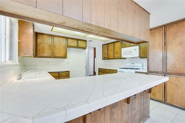 kitchen with white appliances, tile counters, sink, kitchen peninsula, and light tile patterned floors