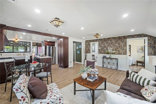 living room featuring light wood-type flooring, sink, and ornamental molding