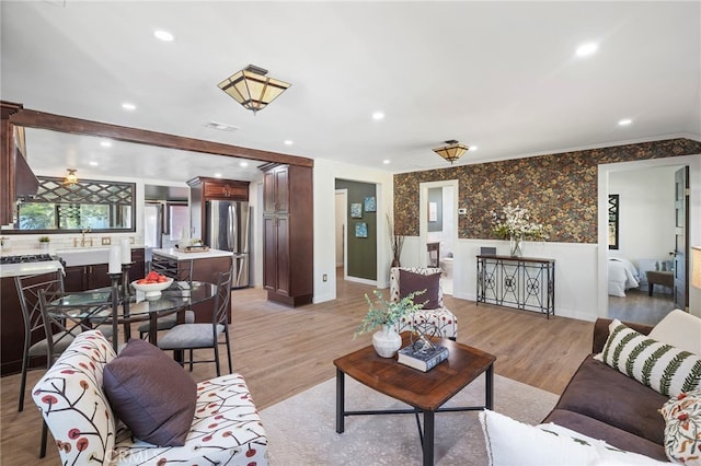 living room featuring ceiling fan, sink, and light hardwood / wood-style flooring