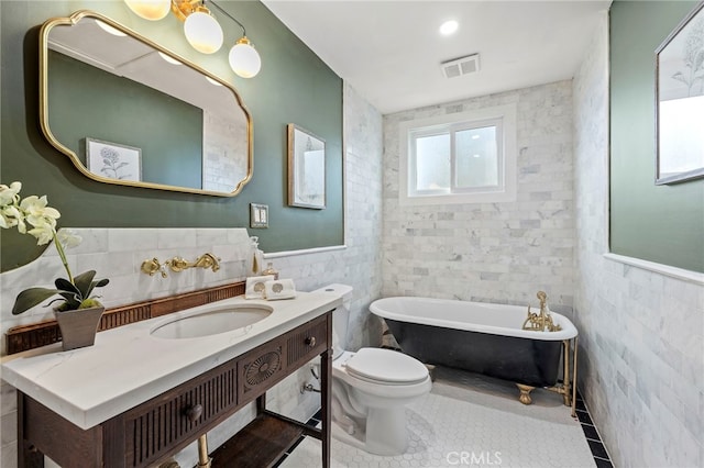 bathroom with tile patterned floors, vanity, tile walls, toilet, and a bathing tub