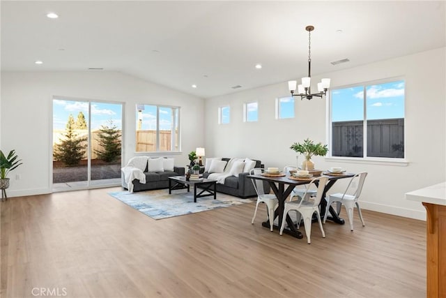 dining space with an inviting chandelier, vaulted ceiling, and light hardwood / wood-style flooring