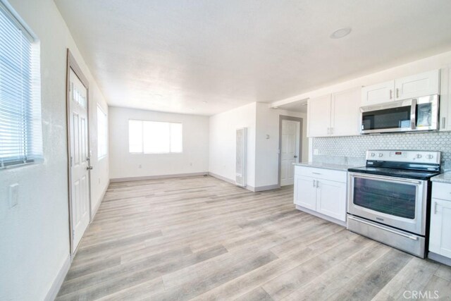 kitchen with stainless steel appliances, decorative backsplash, light hardwood / wood-style floors, and white cabinets