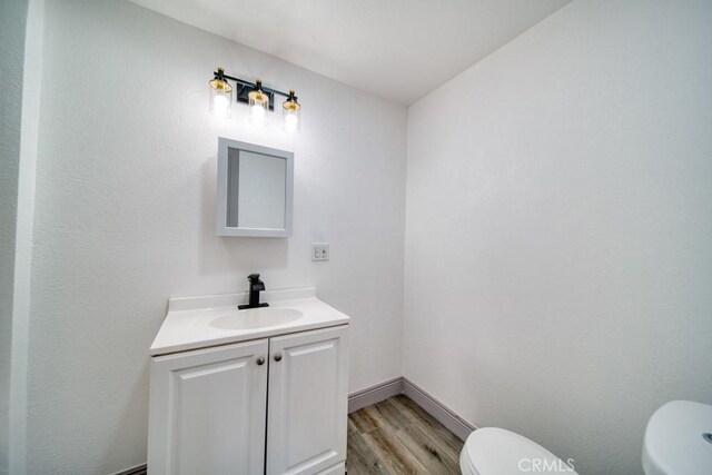 bathroom with toilet, vanity, and hardwood / wood-style floors