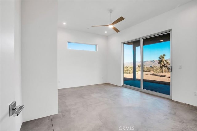 empty room featuring ceiling fan, plenty of natural light, and concrete flooring