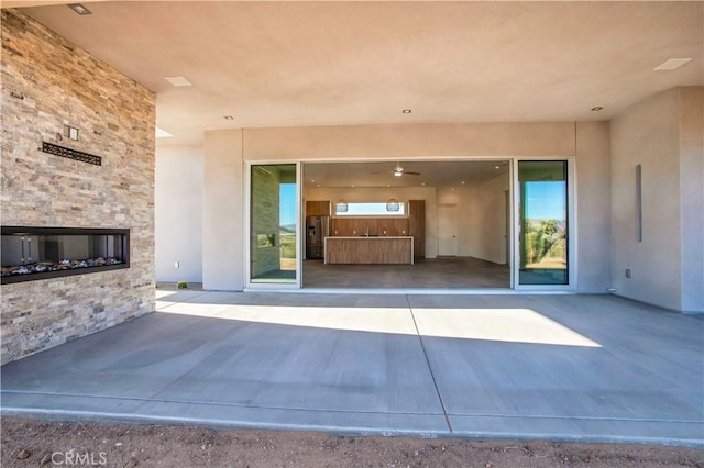 view of exterior entry with a patio and a fireplace