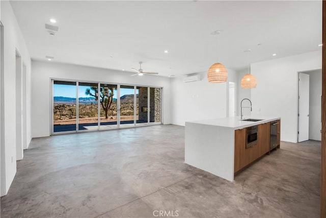 kitchen with pendant lighting, sink, ceiling fan, a center island with sink, and a wall mounted air conditioner