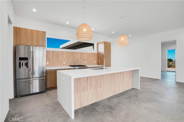 kitchen featuring stainless steel fridge with ice dispenser, a center island with sink, hanging light fixtures, range, and sink