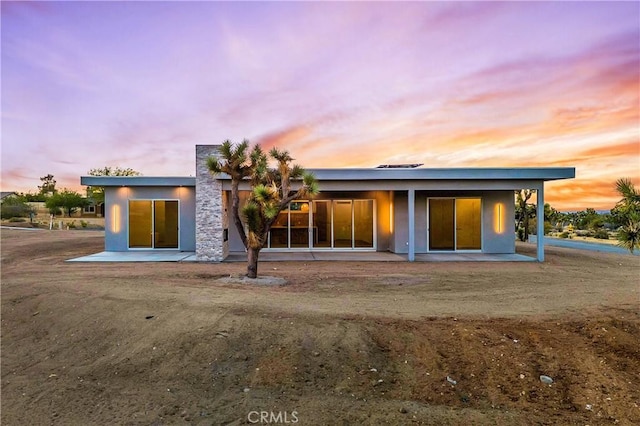 back house at dusk featuring a patio