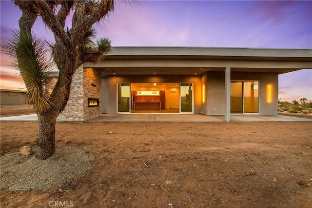 back house at dusk featuring a patio