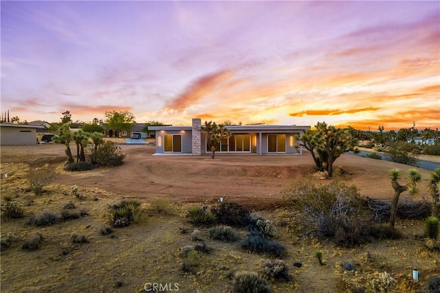 back house at dusk featuring a patio