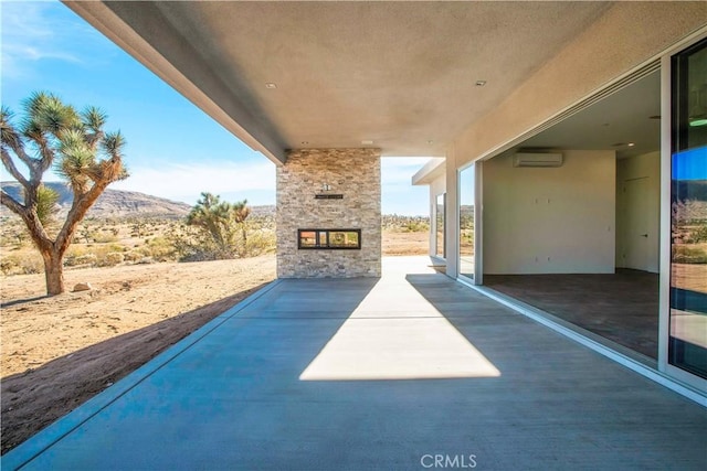 view of patio featuring an AC wall unit, an outdoor stone fireplace, and a mountain view